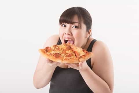 脂っこいピザを食べる女性